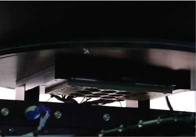 Internal view of LED tester machine showing test head and fixture for component alignment