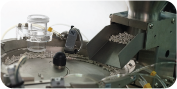 Close-up of a vibrator bowl feeding components into the Glass Turret AOI Machine’s main turret via a parts feeder, illustrating the start of the inspection process.